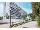 Wide shot of condominium and entrance with mature trees, landscaping and secure gate at 3211 W Swann Ave # 502, Tampa, FL 33609