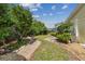Tranquil backyard with stone pathway, lush landscaping, and brick accents surrounding the perimeter at 4044 Priory Cir, Tampa, FL 33618