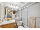Bright bathroom with wood cabinets, a mirror with nautical decor, and a shower with sliding doors at 450 S Gulfview Blvd # 605, Clearwater Beach, FL 33767