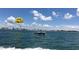 Blue ocean view featuring a boat towing a parasail with yellow smiley face and cityscape background at 450 S Gulfview Blvd # 605, Clearwater Beach, FL 33767