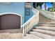 Close-up of two-car garage doors and exterior stairs with white railing on a blue home at 541 Treviso Dr, Apollo Beach, FL 33572