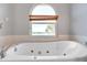 Large soaking tub in a bathroom with a view from an arched window at 8221 118Th Ave, Largo, FL 33773
