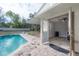 Inviting in-ground swimming pool with brick patio, partially covered seating, and a quaint pool house entrance at 9618 N 55Th St, Temple Terrace, FL 33617