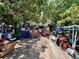 Exterior view of a home's driveway densely packed with disorganized clutter and miscellaneous items under tree cover at 12588 128Th Ave, Largo, FL 33774