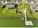 Aerial view of backyard, dock, and walkway lined with palm trees leading to a serene lake at 1407 Tropical Oasis Ave, Plant City, FL 33565