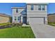 Charming two-story home with a well-manicured lawn and inviting gray color scheme at 1407 Tropical Oasis Ave, Plant City, FL 33565