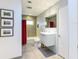 Well-lit bathroom featuring sleek white vanity, gray tiled walls, and red shower curtain accent at 2215 River Ridge Dr, Sarasota, FL 34239