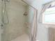 Close-up of shower featuring blue square tiling, neutral shower curtain and flooring, and bright natural light at 2215 River Ridge Dr, Sarasota, FL 34239