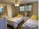Cozy bedroom features two twin beds with bright floral bedding and natural light from large windows at 36416 Cordova Cir, Zephyrhills, FL 33541