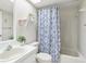 Bright bathroom with patterned shower curtain, bathtub, and a vanity with a stylish plant at 3861 Sailmaker Ln # 0, Holiday, FL 34691