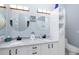 Well-lit bathroom features dual sinks, white cabinets, and round mirrors at 4906 Turtle Creek Trl, Oldsmar, FL 34677