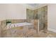 Luxurious bathroom with soaking tub, glass-enclosed shower, and stone tile at 4911 W Melrose S Ave, Tampa, FL 33629