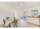 Kitchen and dining area featuring white cabinetry, stainless steel appliances, tile backsplash, and glass table at 6853 Willits Ave, New Port Richey, FL 34655