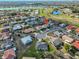 An aerial view of a tan roofed home in a community with lake views and a golf course at 701 Baltusrol Way, Sun City Center, FL 33573
