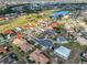 An aerial view of a tan roofed home in a community with lake views and a golf course at 701 Baltusrol Way, Sun City Center, FL 33573