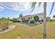 A well-kept lawn surrounds this charming house that has nicely trimmed bushes and Florida palm trees at 701 Baltusrol Way, Sun City Center, FL 33573