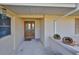 Cozy front porch with a decorative wooden door and neutral stucco wall featuring colorful art pieces at 701 Baltusrol Way, Sun City Center, FL 33573