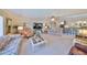 Living room with ceiling fan, light color walls, carpet floor, and view to open kitchen at 701 Baltusrol Way, Sun City Center, FL 33573