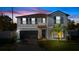 Charming two-story home with a front yard, a black garage door, and palm trees at 7112 Samuel Ivy Dr, Tampa, FL 33619