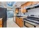 Galley kitchen featuring wood cabinets, granite countertops, black appliances and tile flooring at 7912 Tangerine Dr, Temple Terrace, FL 33637