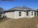 Exterior view of a gray stucco-sided home with white framed windows and trim and new green grass around its base at 8204 Chimney Rock Dr, Webster, FL 33597