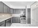 Modern kitchen featuring gray cabinets, stainless steel appliances, white countertops, and marble floors at 851 Bayway Blvd # 904, Clearwater Beach, FL 33767