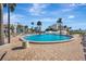 Inviting community pool with a clean brick patio, complemented by lush palm trees and clear blue skies at 851 Bayway Blvd # 904, Clearwater Beach, FL 33767