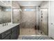 This bathroom features a glass shower, neutral tile, and gray cabinets at 8721 Drummer Plank Dr, Wesley Chapel, FL 33545