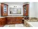 Elegant bathroom with wood cabinets, dual sinks, granite countertops, and a soaking tub with mosaic tile at 9108 Woodbay Dr, Tampa, FL 33626