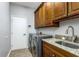 Functional laundry room with wooden cabinets, granite countertop, stainless steel appliances and a white door at 9108 Woodbay Dr, Tampa, FL 33626