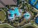 An aerial view of community pools with landscaping, seating, tennis courts, and a pond at 10446 Highland Park Pl, Palmetto, FL 34221