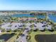 Aerial view showcasing a community clubhouse, pool, tennis courts, and a lake at 10446 Highland Park Pl, Palmetto, FL 34221