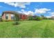 Lush backyard featuring manicured lawn, mature landscaping, and a screened lanai for outdoor enjoyment at 10446 Highland Park Pl, Palmetto, FL 34221