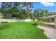 Manicured backyard featuring a large grassy lawn, mature trees, and a white fence at 1180 Eden Isle Ne Blvd, St Petersburg, FL 33704