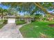 Charming home with a well-manicured lawn, mature trees, and a driveway leading to a single-car garage at 1180 Eden Isle Ne Blvd, St Petersburg, FL 33704