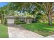 Charming home with a well-manicured lawn, mature trees, and a driveway leading to a single-car garage at 1180 Eden Isle Ne Blvd, St Petersburg, FL 33704