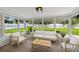 A sun room features a tile floor, a sofa and chairs, and a view of the yard at 1180 Eden Isle Ne Blvd, St Petersburg, FL 33704