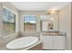 Luxurious bathroom featuring a soaking tub, granite countertop, and ample natural light at 13040 Burns Dr, Odessa, FL 33556