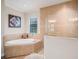 Bright bathroom featuring a soaking tub, tiled walls, a large window, and a glass shower at 13305 Fawn Lily Dr, Riverview, FL 33579