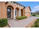 Inviting front entrance with brick pathway leading to a tan colored home with an arched entryway at 13305 Fawn Lily Dr, Riverview, FL 33579