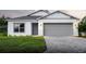 Charming one-story home with a gray brick driveway, an attached two car garage, and manicured lawn at 134 Jade St, Rotonda West, FL 33947