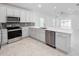 Modern kitchen with stainless steel appliances, white cabinetry, gray backsplash and a spacious quartz countertop at 134 Jade St, Rotonda West, FL 33947
