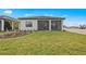 View of the back of the house with a screened patio, a lush green lawn, and well-maintained landscaping at 17069 Moonflower Dr, Venice, FL 34293