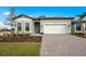 Charming single Gathering home with a light green exterior and a well-maintained paver driveway at 17069 Moonflower Dr, Venice, FL 34293