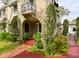 Inviting home exterior featuring a charming arched doorway, a small balcony, and vibrant, colorful landscaping at 215 Willowick Ave, Temple Terrace, FL 33617