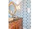 Unique powder room with blue patterned wallpaper, gold hardware, and elegant vanity with decorative sink at 2514 W Morrison Ave, Tampa, FL 33629