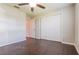 Bright bedroom featuring a ceiling fan, closet, and rich dark wood-look flooring for a warm, inviting feel at 29636 Tee Shot Dr, San Antonio, FL 33576