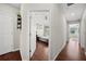 Hallway featuring wood floors, white doors, leading to bedrooms with natural light and comfortable space at 30045 Southwell Ln, Wesley Chapel, FL 33543