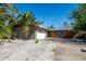 Charming single-story home featuring a lush tropical landscape, a paved driveway, and a bright, inviting entryway at 305 160Th Ter, Redington Beach, FL 33708
