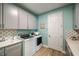Bright laundry room features gray cabinets, modern washer and dryer, and stylish backsplash at 3915 Farm Garden Ct, Lakewood Ranch, FL 34211